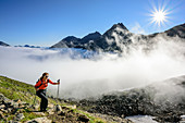 Woman hiking ascending towards Wilder Freiger, fog in the valley, Wilder Freiger, Stubai Alps, Tyrol, Austria