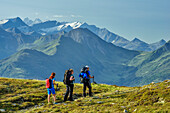 Drei Personen wandern am Pinzgauer Spaziergang, Hohe Tauern mit Großglockner im Hintergrund, Pinzgauer Spaziergang, Kitzbüheler Alpen, Salzburg, Österreich