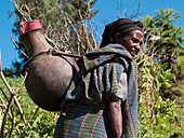 Eine Frau trägt einen großen traditionellen Topf mit Wasser auf dem Rücken, Äthiopien, Afrika
