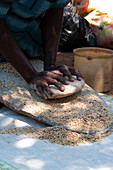 Eine Frau, die zwei Steine ??benutzt, um Korn zu mahlen, Uganda, Afrika