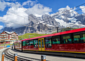 Ein Zug nähert sich der Station Kleine-Scheidegg, unter der beeindruckenden Nordwand von Eiger und Mönch, Berner Alpen, Schweiz Europa