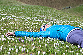 Mädchen ist entspannend auf Blumenwiese (Alp Otro, Alagna Valsesia, Provinz Vercelli, Piemont, Italien, Europa)