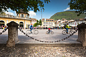 ein besonderer Blick auf den Waltherplatz voller Menschen und mit drei Radfahrern im Vordergrund, Bozen, Südtirol, Trentino-Südtirol, Italien, Europa