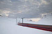 Bernina Express fährt in der verschneiten Landschaft im Morgengrauen Bernina Pass Kanton Graubünden Engadin Schweiz Europa