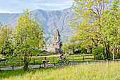 Cyclists on mountain bike around the Abbey of San Pietro in Vallate Piagno Sondrio province Valtellina Lombardy Italy Europe