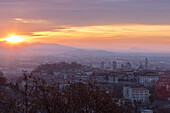 Blick auf die mittelalterliche Altstadt Città Alta auf einem Hügel, umrahmt vom feurigen orangefarbenen Himmel im Morgengrauen Bergamo Lombardei Italien Europa