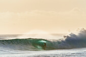 A surfer gets barreled before sunset