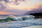 Eine Welle, die während des Sonnenaufgangs an Pounders Strand, auf der Ostseite von Oahu, Hawaii, zum Ufer bricht.