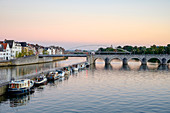 Foto der Maas mit Brücke, Boote und Gebäude am Ufer, Maastricht, Limburg, Niederlande