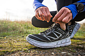 Woman tying her shoe for a trail run on a coastal path in Newport, Rhode Island, during early spring