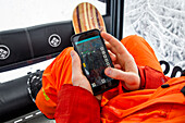 Snowboarder mit einem Telefon zur Überprüfung der freien Fahrbahn im Lift