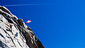 Eine Person springt von einer Klippe in einem Wingsuit in den Alpen