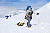 Ski-Bergsteiger und Rangers auf dem Weg zu 14.000 Meter auf Denali in Alaska. Kletterer auf dem höchsten Gipfel Nordamerikas tragen ihre Lasten in Rucksäcken und auf Schlitten.