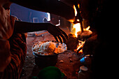 Ester Hodari, age 22 years old, cooks dinner using the traditional three-rock cook stove with a fire in the middle. These cookstoves use a lot of fuel, firewood, and produce a lot of smoke. Ester told us that cooking with this type of stove made her eyes 