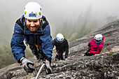 Ein Mann greift nach der Metallsprosse beim Klettern der Via Ferrata in Squamish, British Columbia.