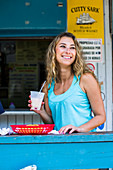 Lächelnde junge Frau an der Bar eines kleinen Restaurants