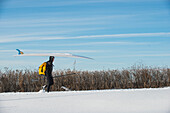 Paddleboarder Carrying Paddleboard Into The Cold Atlantic Water On A Sunny Day