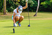 Young woman placing golf ball on tee