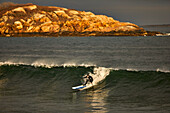 A surfer surfing on waves at Good Harbor Beach in Gloucester, Massachusetts
