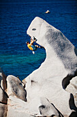 Man climbing on rocks near sea, Capo Testa, Sardinia, Italy