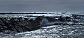 France, panoramic view of a stormy sea crossing a rock slant. Lighthouse right background