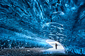 View from inside ice cave under the Vatnajokull Glacier with person for scale, near Jokulsarlon Lagoon, South Iceland, Polar Regions
