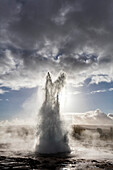 Strokkur-Geysir, der gegen stürmischen Himmel, Geysir, Südwest-Island, Polargebiete ausbricht