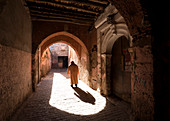 Local man dressed in traditional djellaba walking through archway in a street in the Kasbah, Marrakech, Morocco, North Africa, Africa