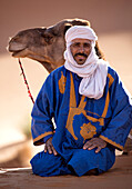 Berber man with camel, resting in the Erg Chebbi Sand sea, part of the Sahara Desert near Merzouga, Morocco, North Africa, Africa
