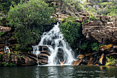 Photograph of man bathing in idyllic scenery with Cachoeira Serra Morena waterfall in Serra do Cipo National Park, Minas Gerais, Brazil