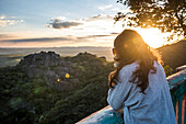 Photograph of woman looking at view of nature at sunset in Belvedere by MG-010 highway at Serra do Cipo National Park, Minas Gerais, Brazil