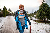 Mother walking with baby in carrier at Christmas tree farm, Langley, British Columbia, Canada