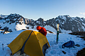 Fotografie des Mannes stehend nahe kampierendem Zelt bei Sahale Peak, Nordkaskaden-Nationalpark, Washington State, USA.