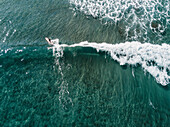 Aerial view of female surfer surfing in clear sea, Tenerife, Canary Islands, Spain