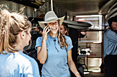 Young freckled woman wearing cowboy hat talking on mobile phone and smiling, Portland, Maine, USA