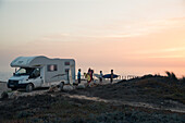Five young surfer standing at their camper at the beach Praia da Amoreira,  Aljezur, Faro, Portugal