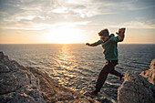 Young man jumping on a cliff at the beach Praia da Amoreira,  Aljezur, Faro, Portugal