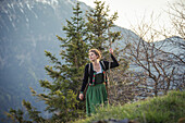 Young woman in traditional costume hiking on Falkenstein in Allgaeu, Pfronten, Bavaria, Germany
