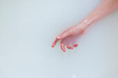 Hand einer kaukasischen Frau im Milchbad