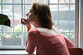 Pensive Caucasian woman daydreaming near window