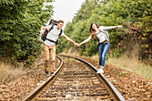 Caucasian couple balancing on train tracks