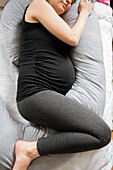 Caucasian expectant mother laying on bed with support pillow