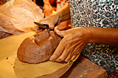 Mixed race woman shaping clay mask in art studio
