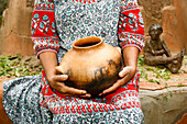 Woman sitting and holding clay pot