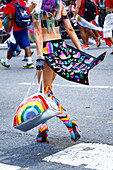 Person wearing high heel boots carrying purse in pride parade
