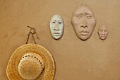 Clay masks and hat hanging on wall