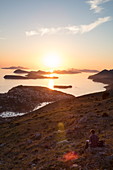 Man reads book with view across Lapad Peninsula and islands seen from hillside near top of Dubrovnik Gondola at sunset, Dubrovnik, Dubrovnik-Neretva, Croatia