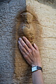 Hand touches carving of an owl worn smooth on outside wall of Eglise Notre Dame cathedral, Dijon, Côte-d'Or, Bourgogne-Franche-Comté, France