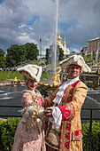 Paar in historischen Kostümen posiert vor der Großen Kaskade am Palast von Schloss Peterhof, nahe Sankt Petersburg, Russland, Europa