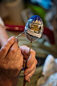 Detail of hand of woman painting souvenir Faberge-style egg at Mandrogi crafts village, Mandroga, Svir river, Russia